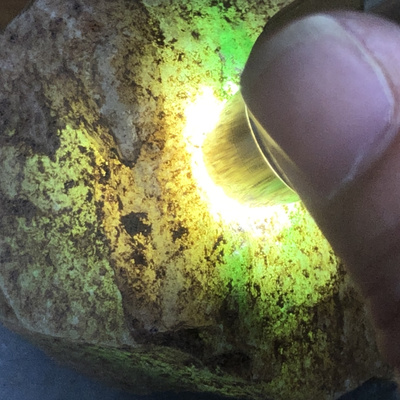 一块木那老坑山料翡翠原石,打灯通体全透.阳绿色带清